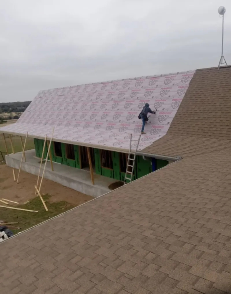 Worker preparing underlayment for a metal roof installation in Cranford